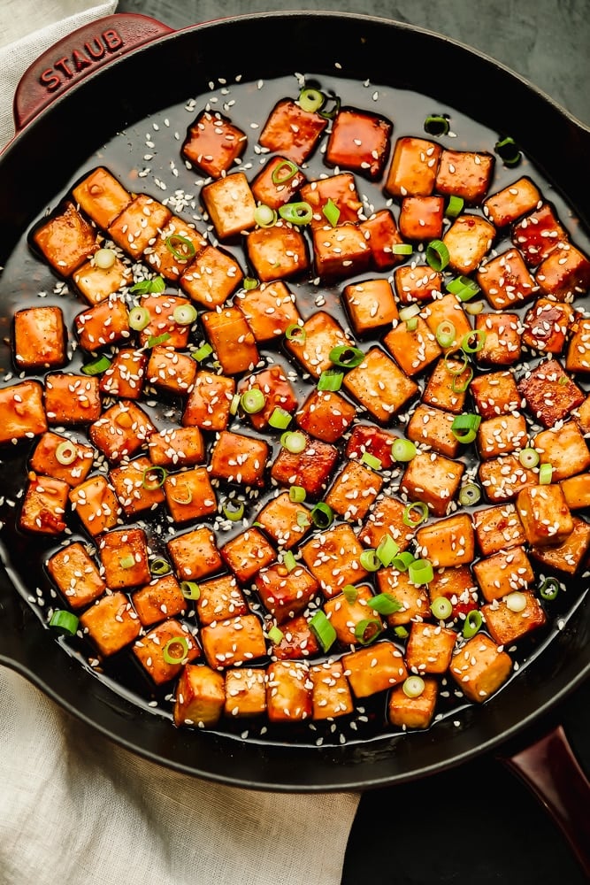 baked tofu cubes covered in a brown sauce in a large black skillet