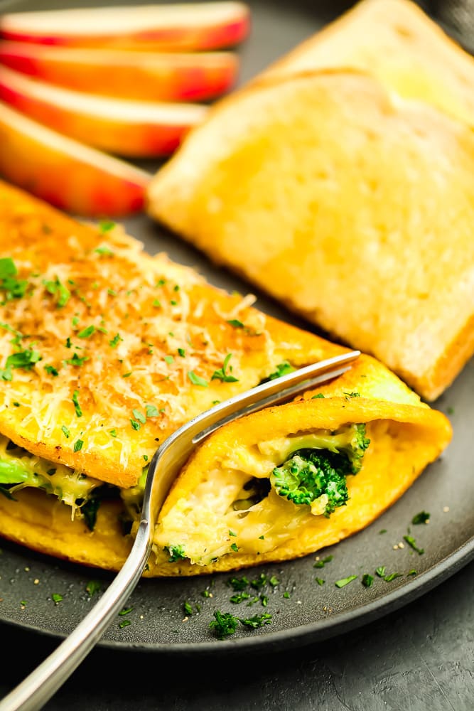 fork cutting into a cooked omelette on a grey plate