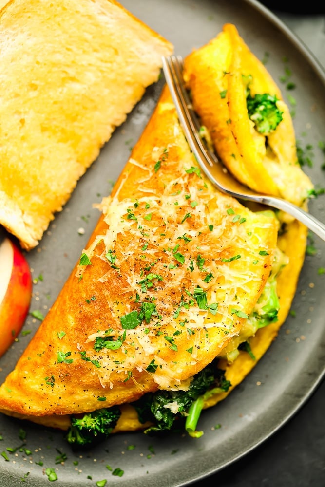 fork cutting into a cooked omelette on a grey plate