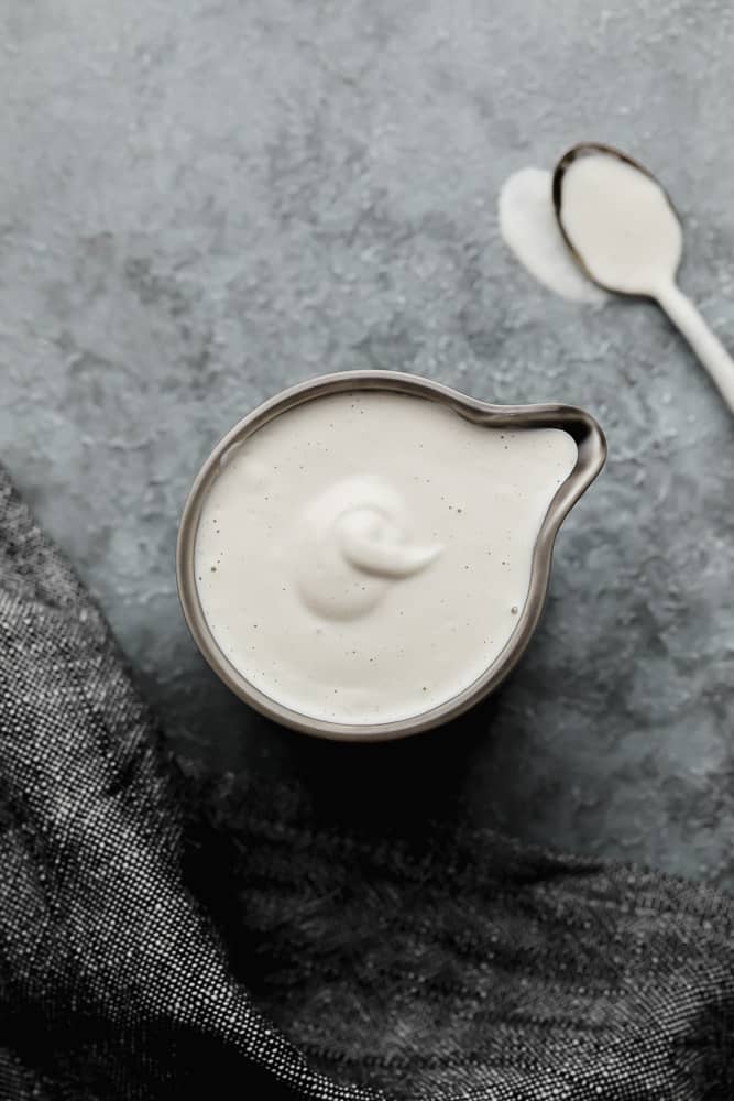 looking down on a grey pitcher with cream and a spoon in the background