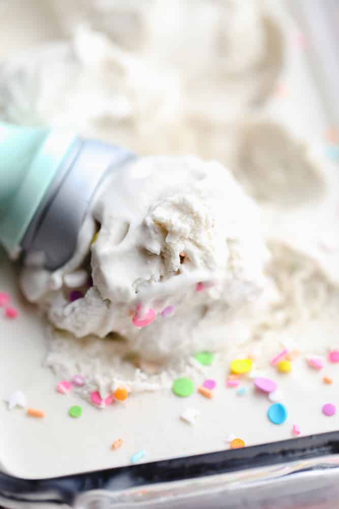 ice cream scoop scooping vanilla ice cream out of a glass dish