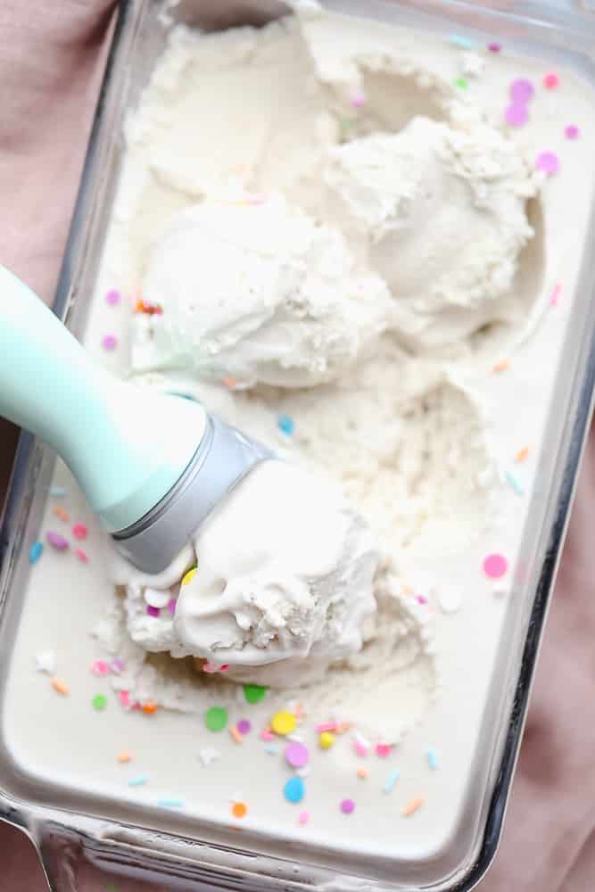 ice cream scoop scooping vanilla ice cream out of a glass dish