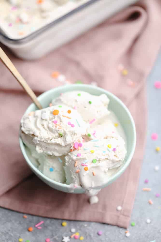 teal bowl with scoops of vanilla ice cream and colorful sprinkles on top