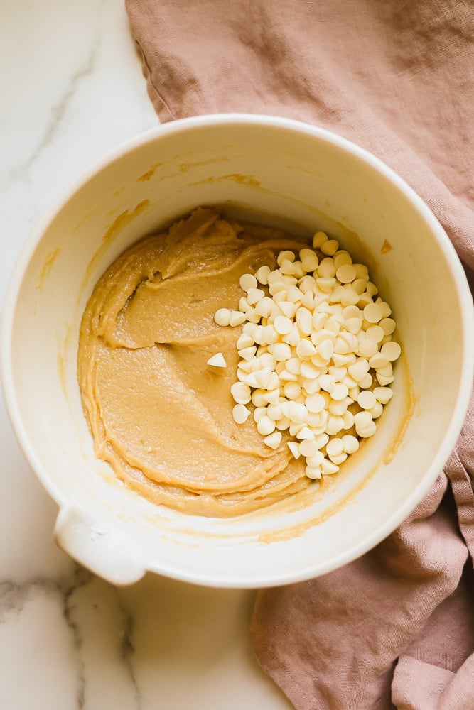 white bowl with light brown batter and white chocolate chips