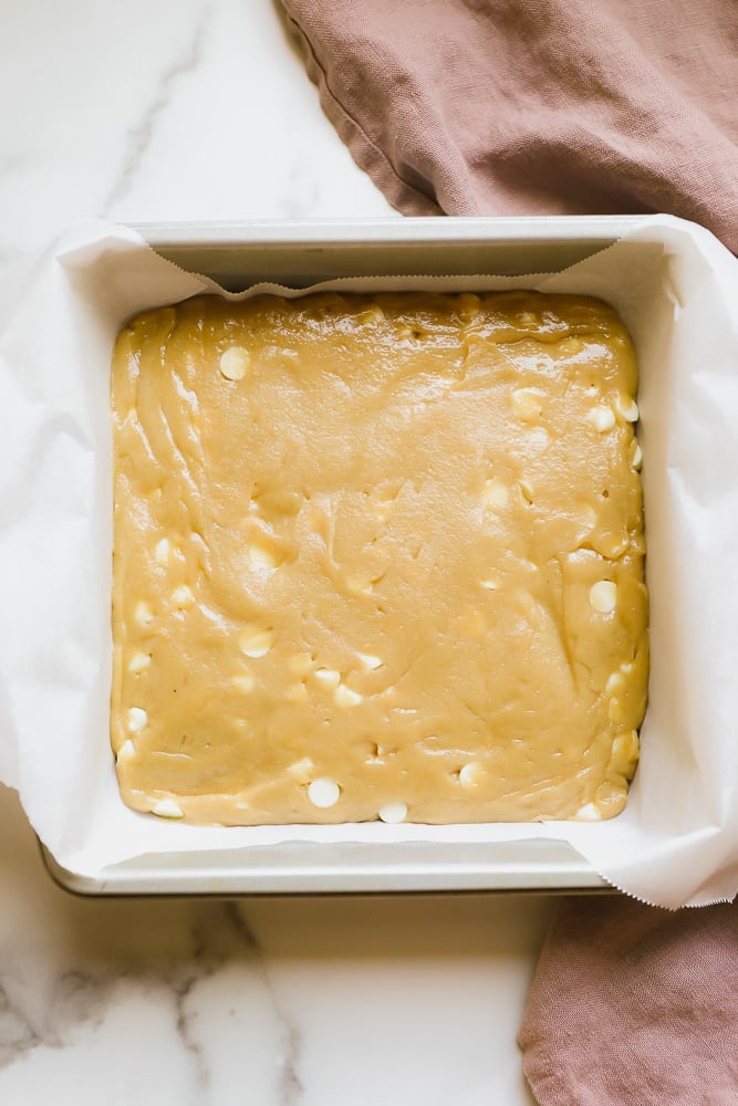 light brown batter in a parchment lined baking dish