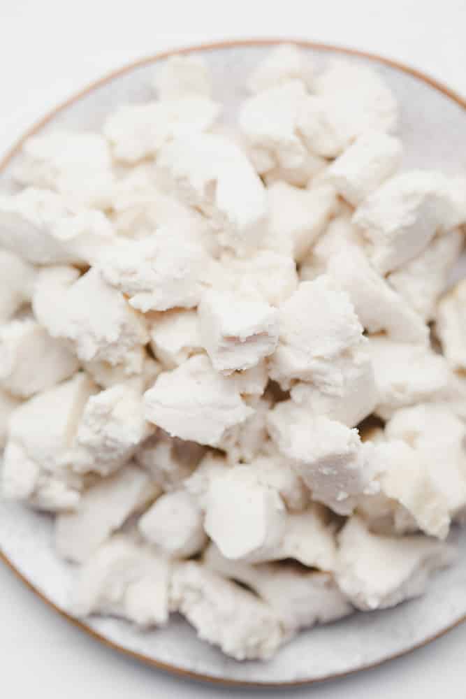 crumbled white cubes of vegan feta cheese on a white plate