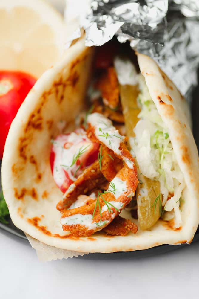 close up on a vegetable shawarma wrapped in tin foil.