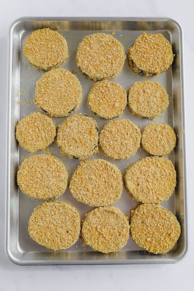 eggplant slices coated in crumbs lined on a baking tray