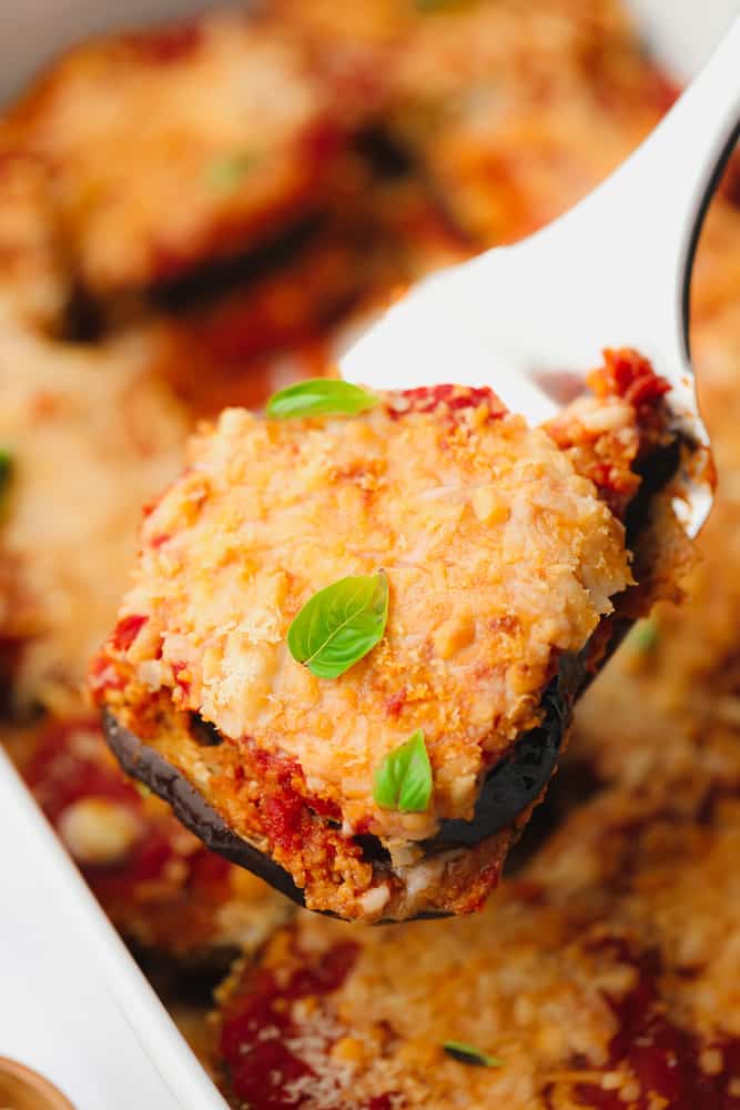 close up on a scoop of eggplant parmesan with melted cheese and herbs on top.