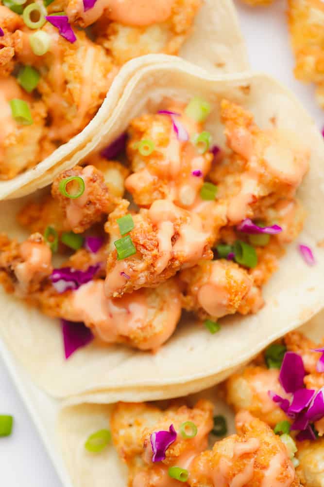 fried cauliflower with orange sauce, purple cabbage, and green herbs in a flour tortilla