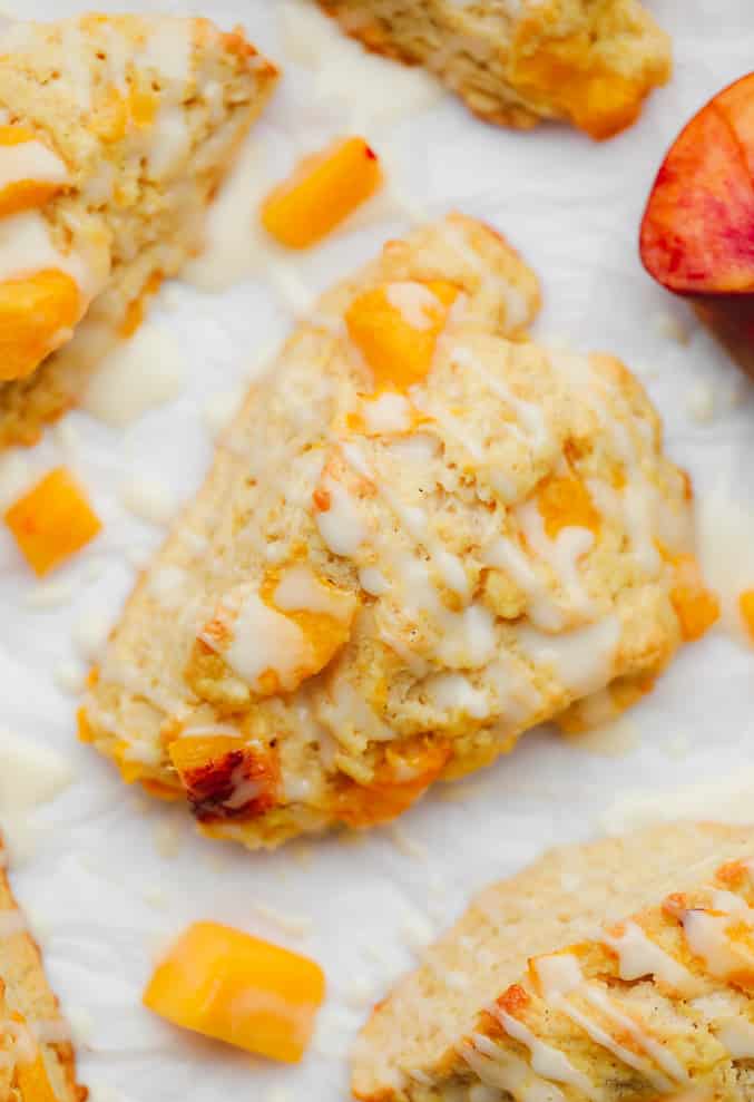 close up on a baked peach scone with a white glaze on top