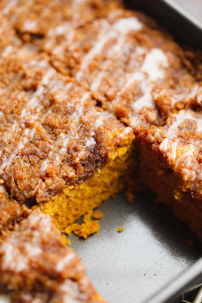 close up on a cut slice of brown pumpkin coffee cake in a metal baking tin.