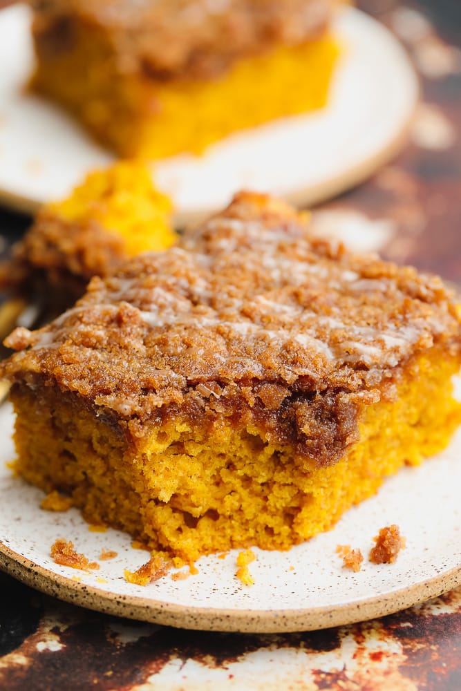 close up on a square slice of orange pumpkin coffee cake on a white plate.