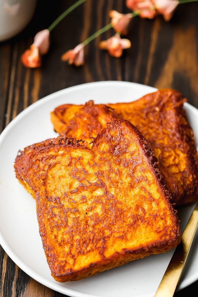 2 slices of vegan pumpkin french toast on a white plate.