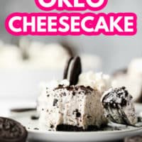 pinterest image of a fork taking a bite from a slice of a vegan oreo cheesecake on a white plate.