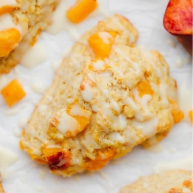 close up on a baked peach scone with a white glaze on top