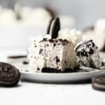 fork taking a bite from a slice of a vegan oreo cheesecake on a white plate