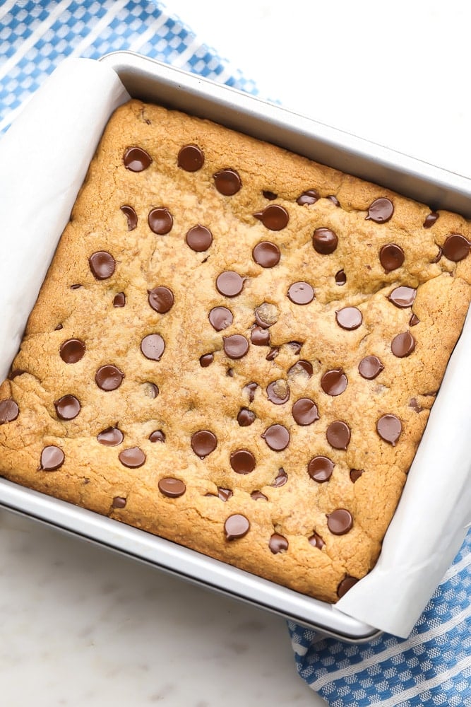 uncut cookie bars in a pan, blue towel in background