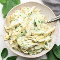 bowl of pasta with spinach in background