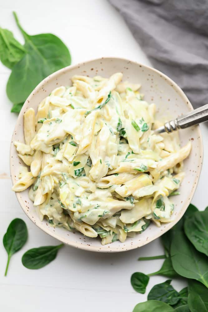 bowl of pasta with spinach in background