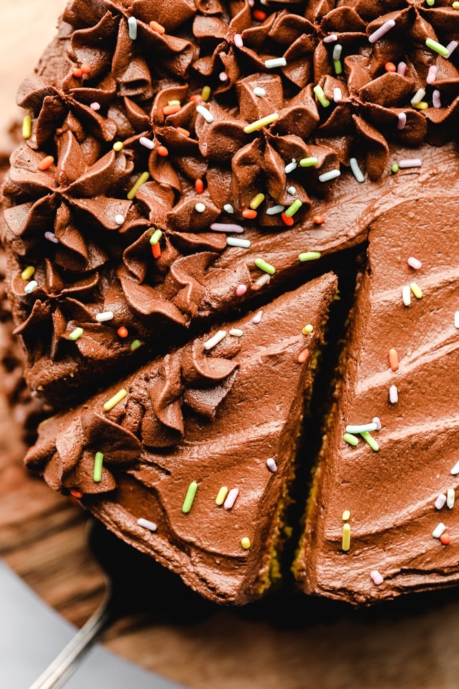 Removing a slice of chocolate-frosted cake.