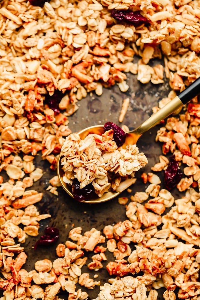 a spoonful of granola surrounded by more granola on a baking sheet.