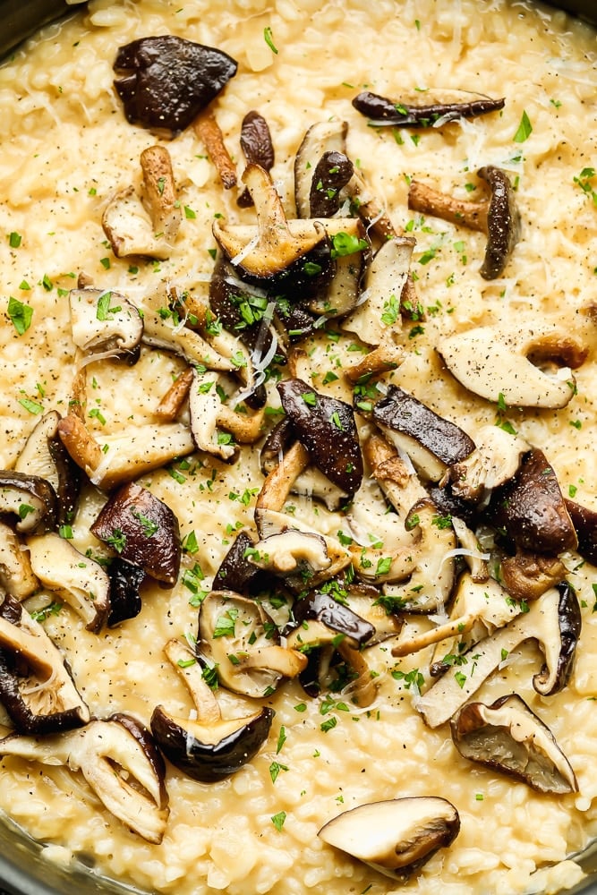 Close up on cooked mushrooms on top of creamy yellow risotto.