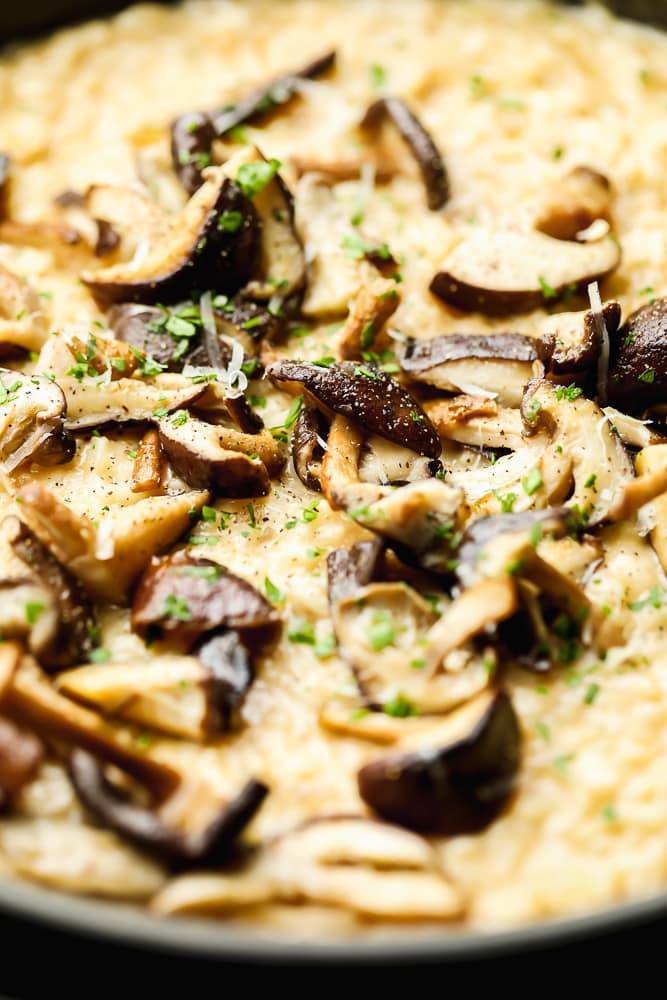 Close up on cooked mushrooms on top of creamy yellow risotto.