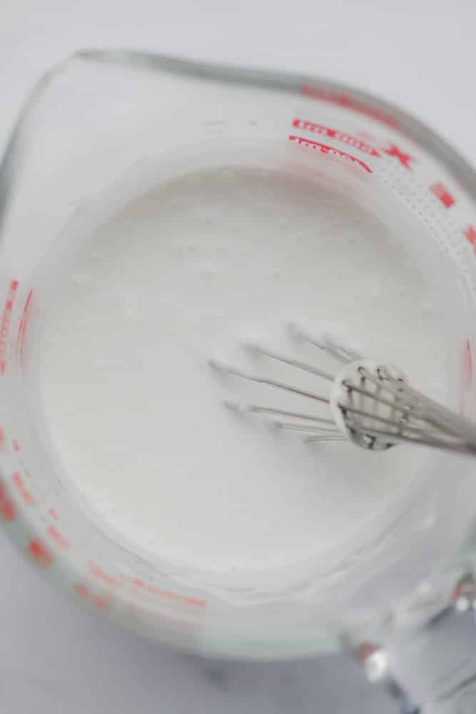 Whisking milk in a glass measuring cup.