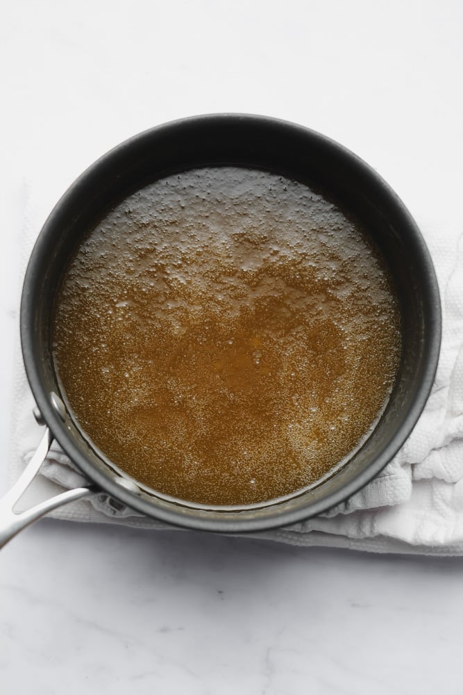 a thin golden brown sauce in a black saucepan.