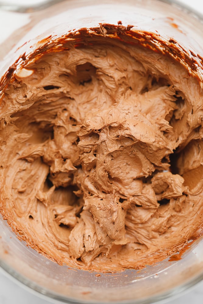 Whipped chocolate frosting in a glass bowl.