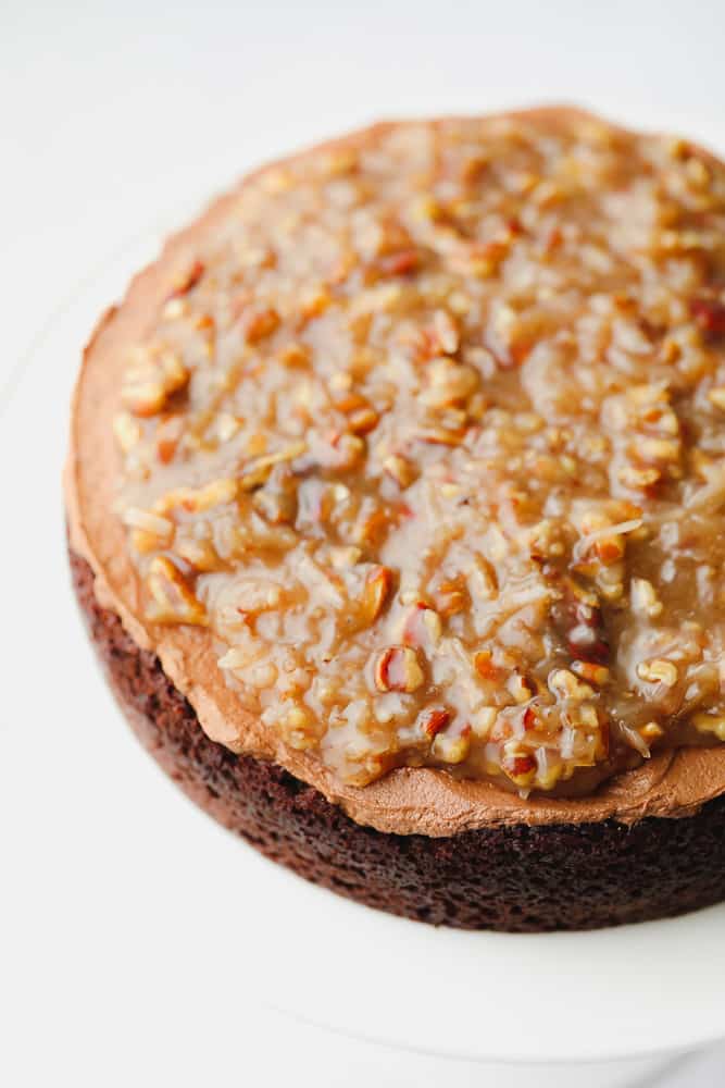 A layer of chocolate cake with chocolate frosting and a pecan caramel sauce on top.