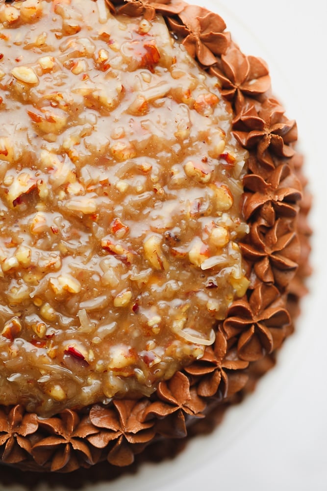 Close up on a frosted chocolate cake with a pecan caramel sauce on top.