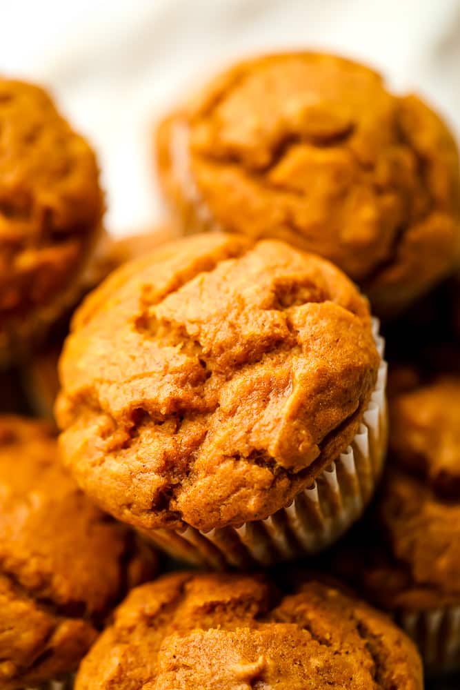 lots of vegan pumpkin muffins on top of each other, white background