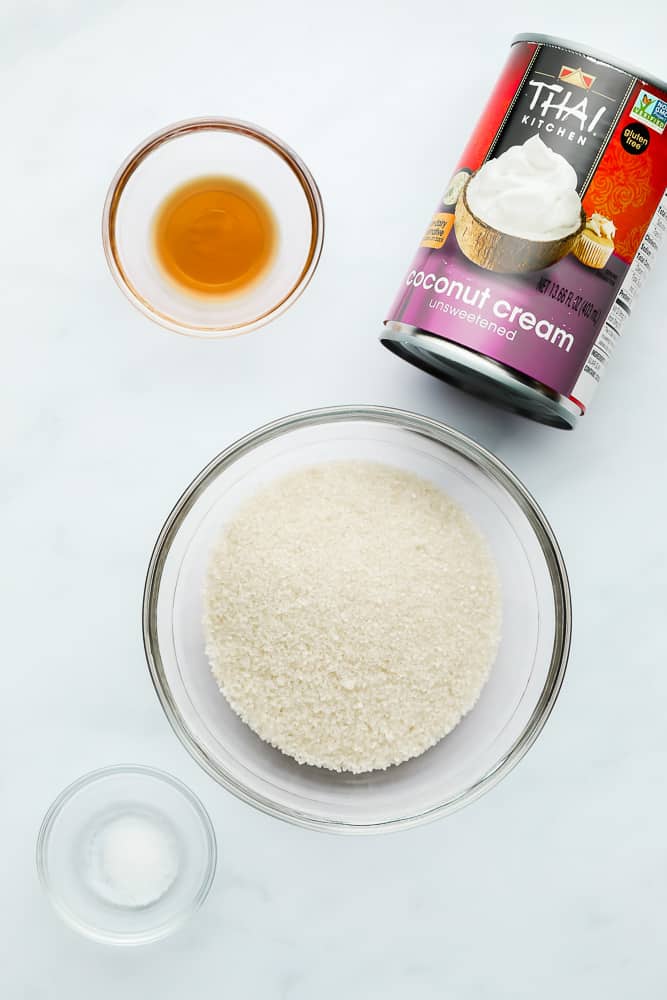 a can of coconut cream next to small glass bowls filled with sugar, vanilla, and salt.