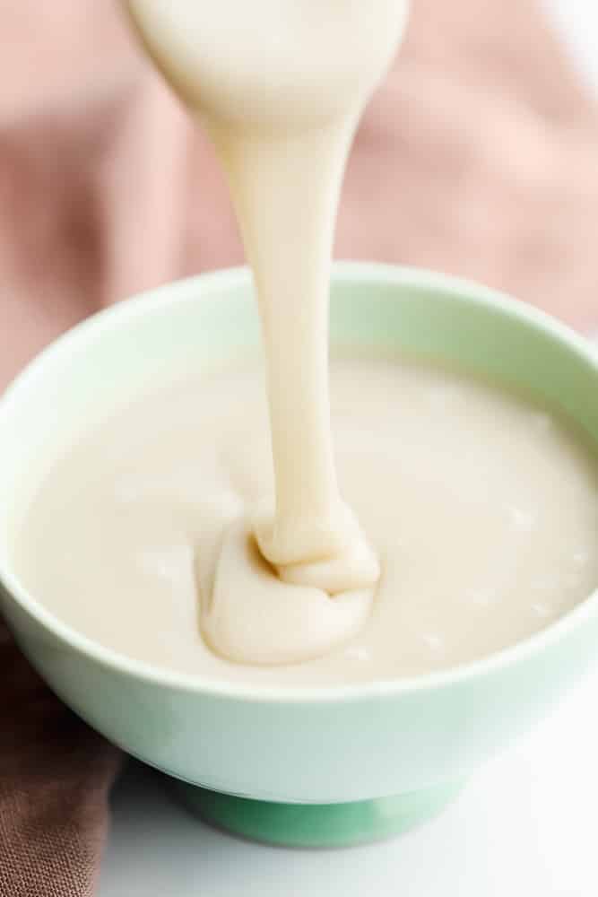 Pouring a creamy white liquid into a green bowl.