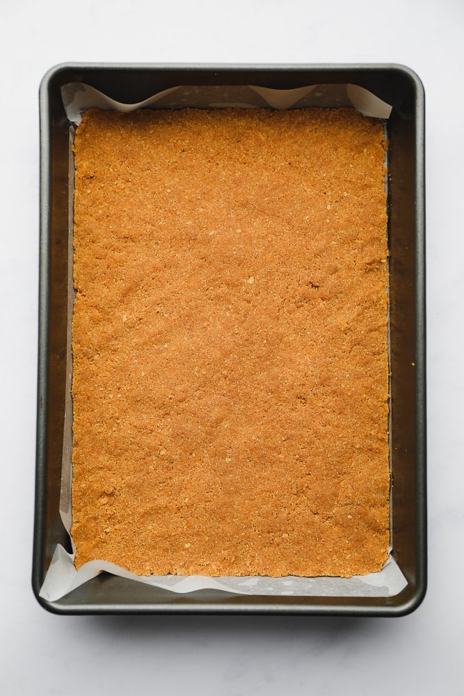 a graham cracker crust pressed into the bottom of a metal baking pan.