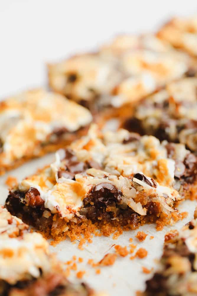 a bite missing from a cookie bar with toasted marshmallows, coconut, and chocolate on top.