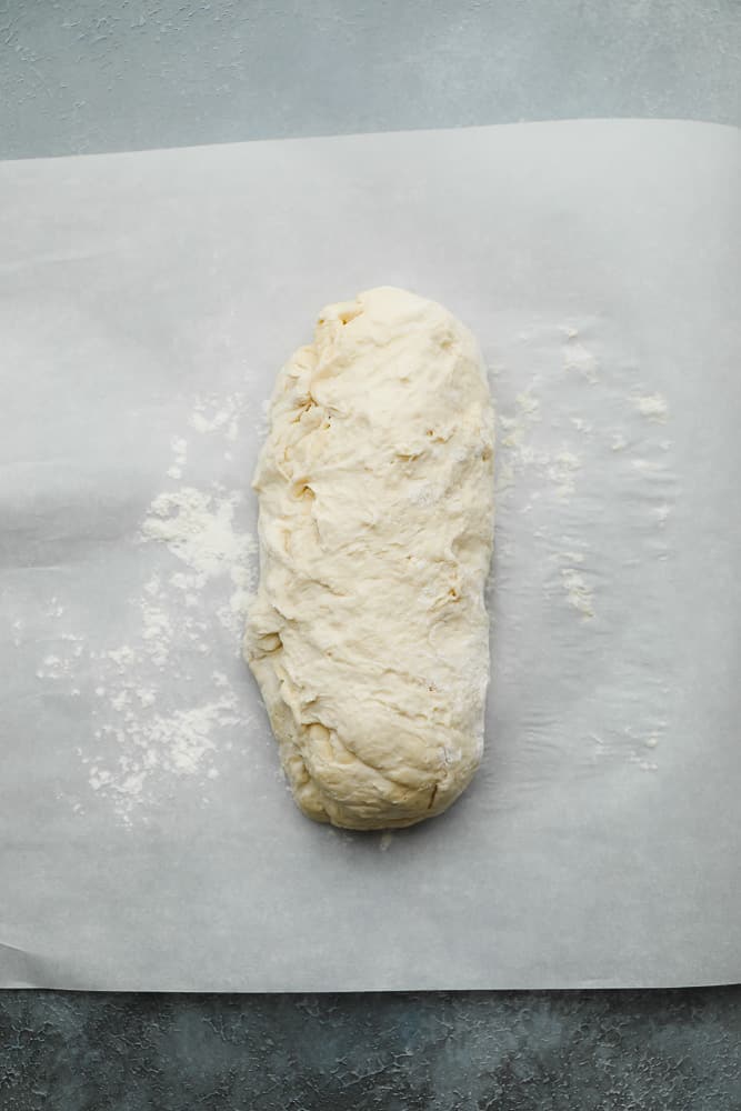 a log of raw bread dough on a piece of parchment paper.