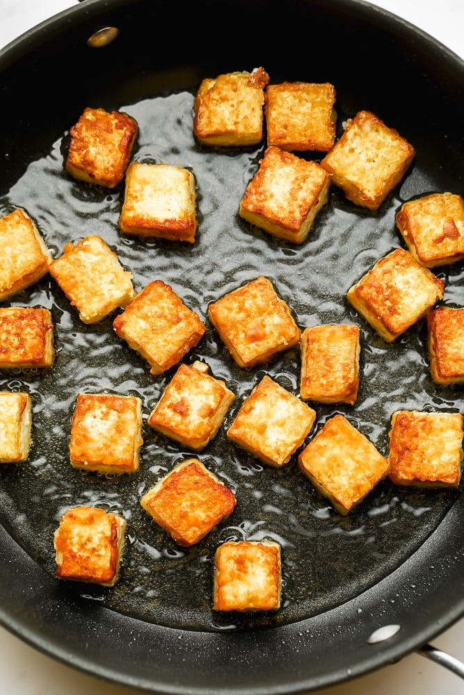 golden brown fried tofu in a pan with oil