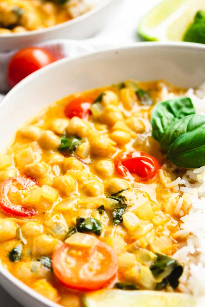 close up of a bowl of curried beans, tomatoes and basil