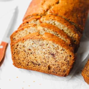 square image of a loaf of vegan banana bread sliced in white background