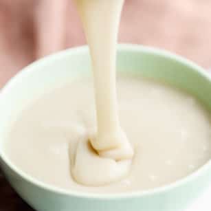 square image of pouring white sauce into green bowl