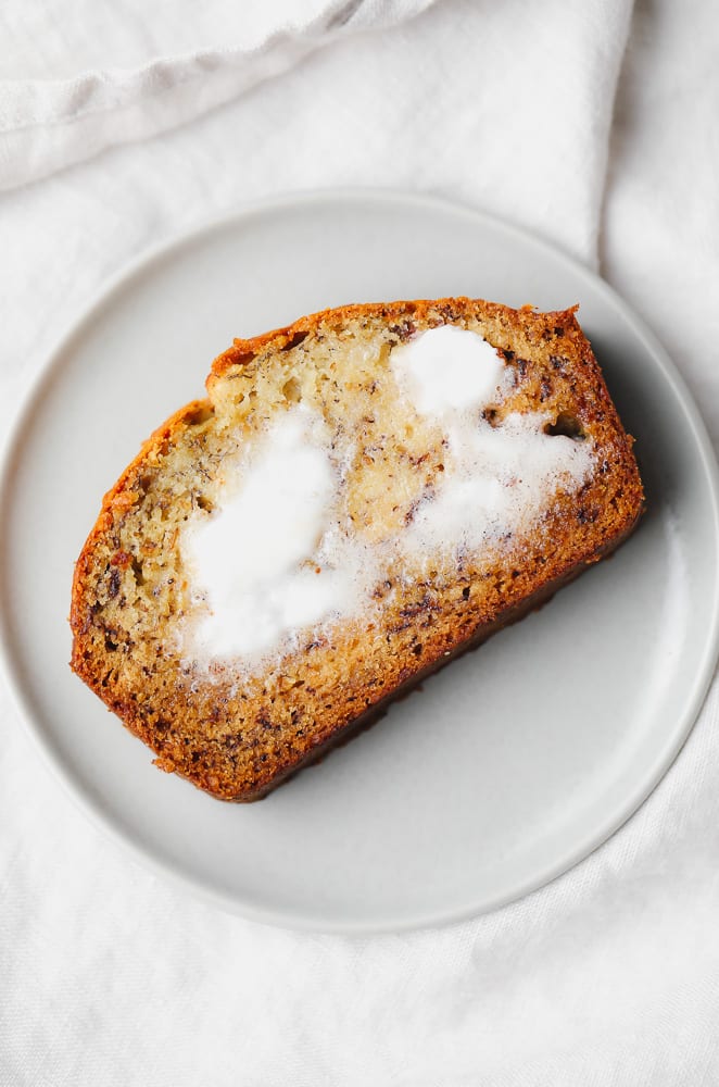 slice of vegan banana bread with butter melting on it, grey plate
