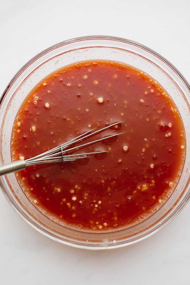red sauce and a small whisk in a glass bowl.