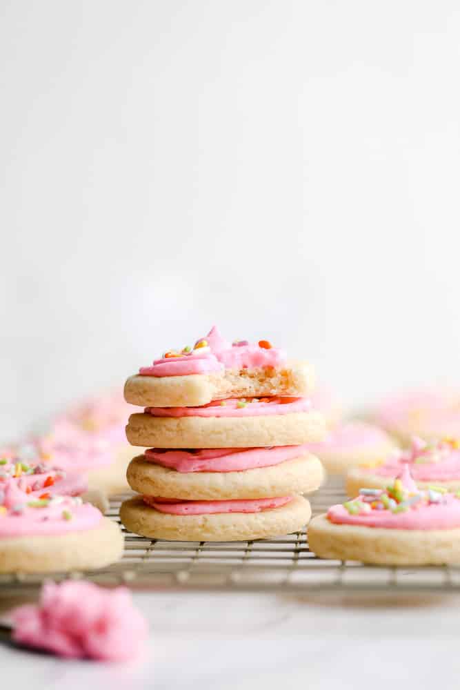 stack of 4 pink frosted cookies with sprinkles