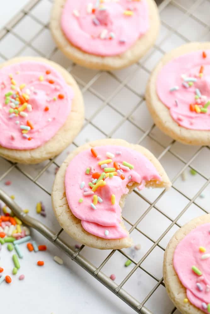 rack with many cookies, one with bite taken out, with sprinkles