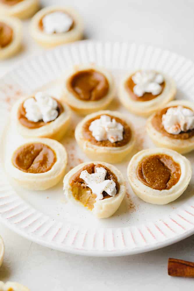 many little pumpkin pies on a plate, one with bite taken