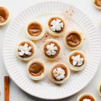 plate with mini pumpkin pies on it, some with whipped cream