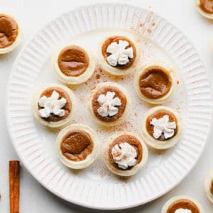 plate with mini pumpkin pies on it, some with whipped cream